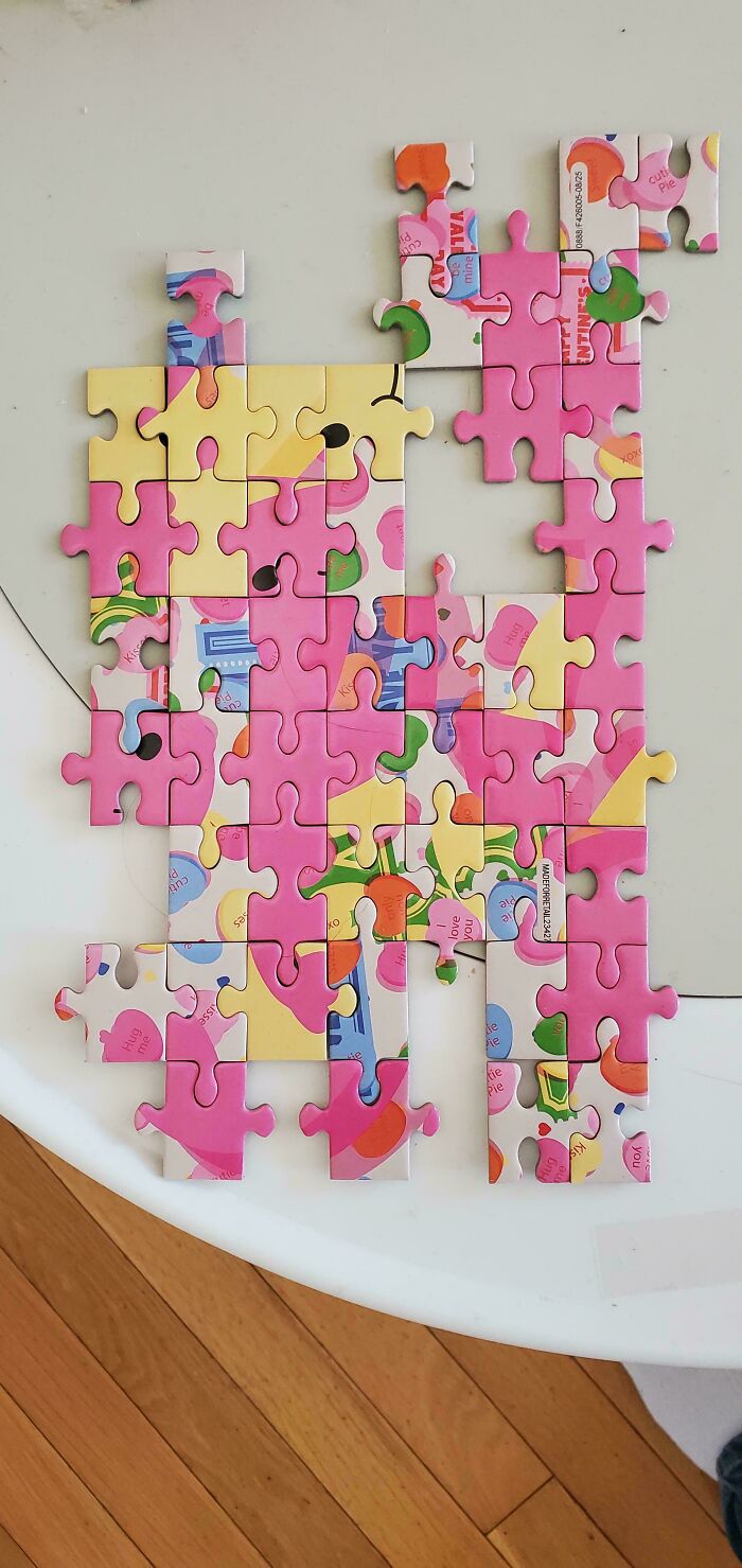 A colorful jigsaw puzzle, partially assembled on a white surface, with many pink and yellow pieces. Great for dads.