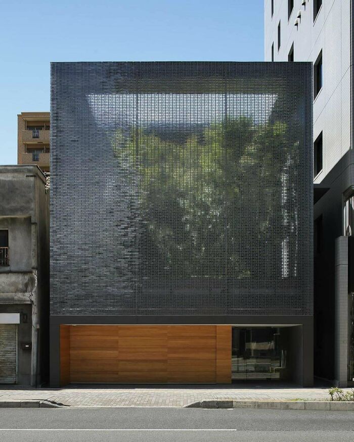 Modern architecture building with a textured glass facade and wooden lower level, showcasing impressive building design for architecture lovers.