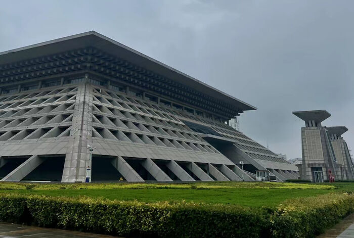 A striking, modern concrete building with triangular patterns and a unique roofline, alongside another complementary structure, for architecture lovers.