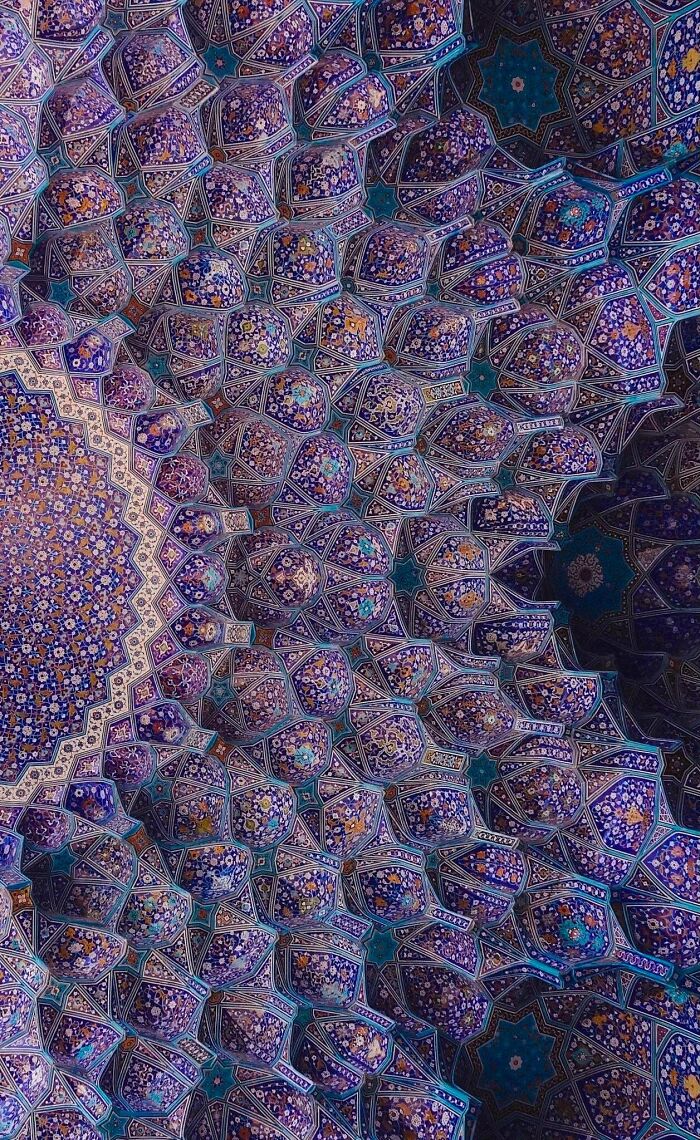 Intricate muqarnas architecture with blue and purple floral tile patterns. Impressive building design for architecture lovers.