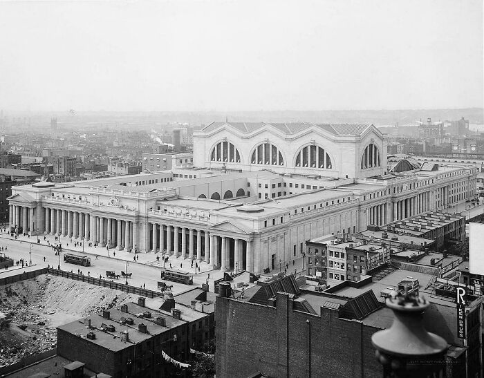 Historic black and white aerial view of a grand building with impressive architecture, surrounded by city streets.