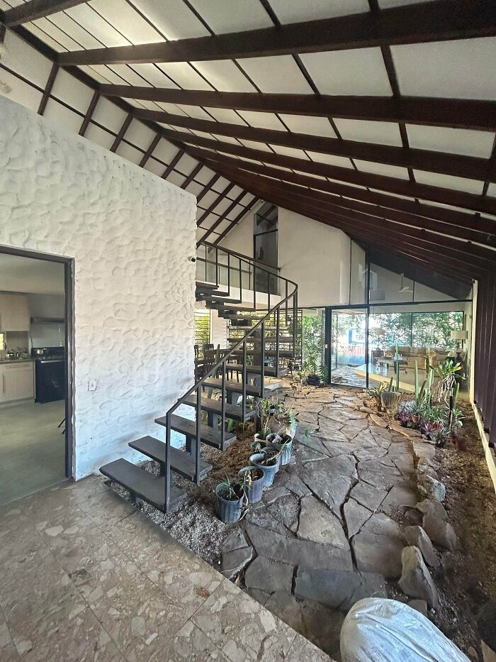 A unique building interior with a high vaulted ceiling, spiral staircase, and indoor garden, showcasing impressive architecture.