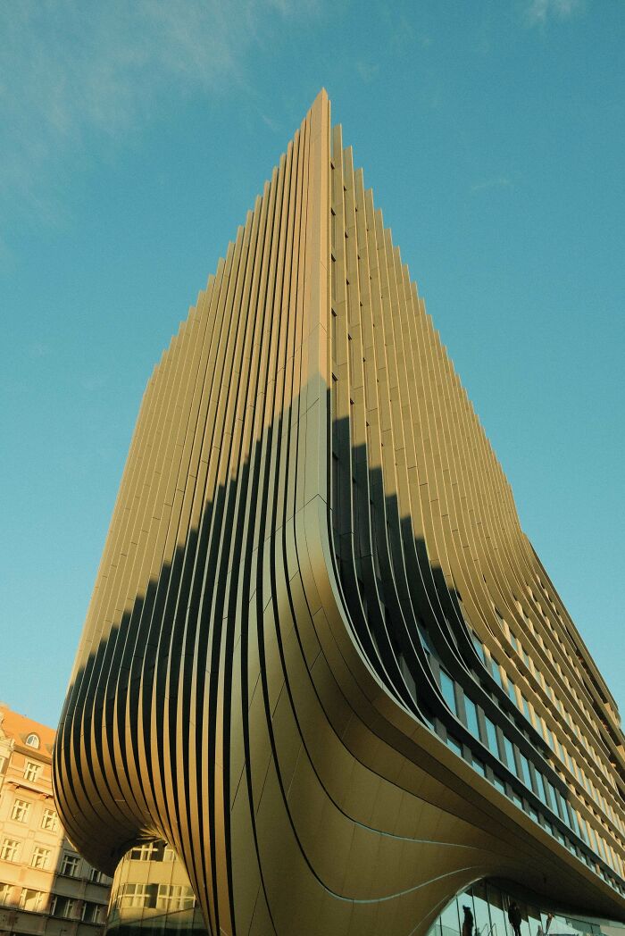 Captivating modern architecture building with a unique ribbed design, curving gracefully under a clear blue sky. Architecture lovers will appreciate this.