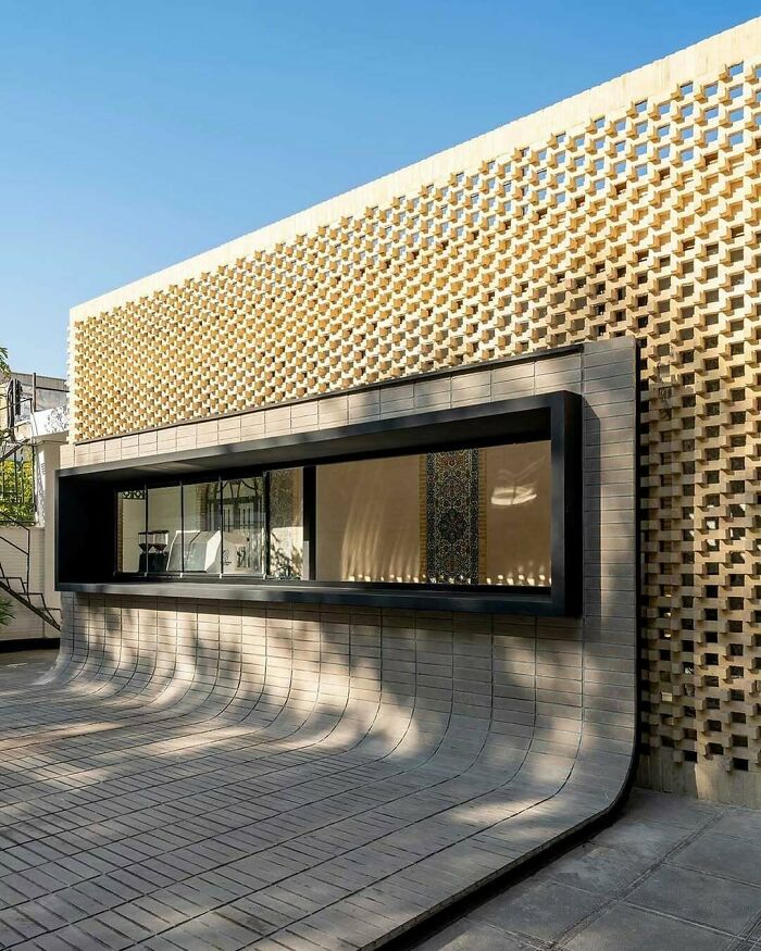 Impressive architecture featuring a textured brick facade and a flowing, curved concrete entryway, truly a building to admire.