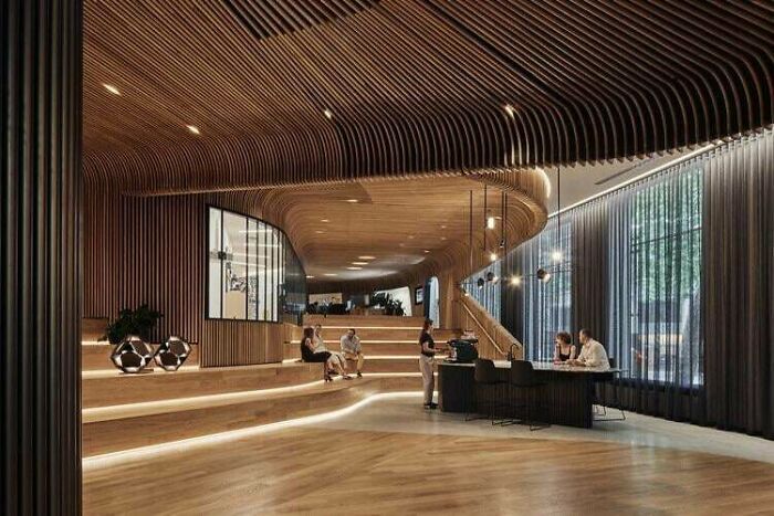 Architecture lovers impressed by this stylish interior with curved wood panels, tiered seating, and modern lighting.