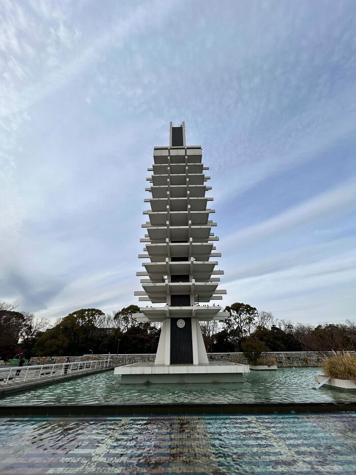Modernist architecture building with stacked platforms, a clock, and a water feature. Impressive for architecture lovers.