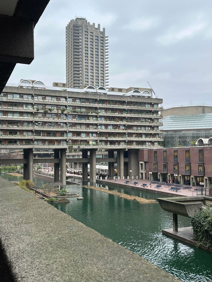 Impressive Brutalist architecture with a high-rise building and a multi-tiered structure overlooking a canal. Architecture lovers will appreciate this building.