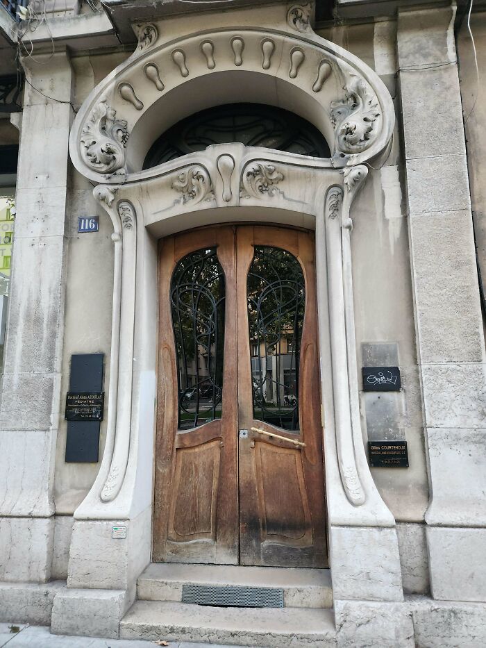 An ornate Art Nouveau door with carved stone archway and decorative ironwork windows, showcasing impressive building architecture.
