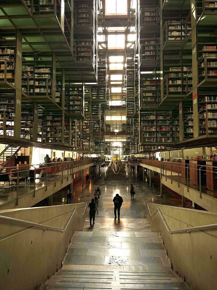 Vast library with soaring shelves, natural light, and people browsing, a building that impresses with its architecture.