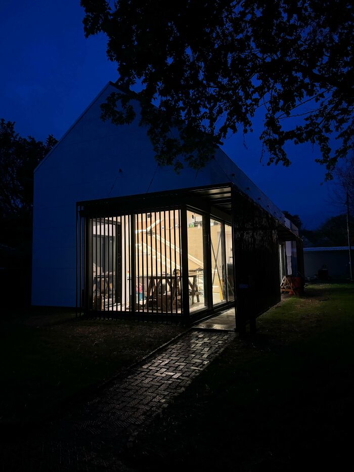 A modern architecture building with bright interior lights shining through large windows at dusk.