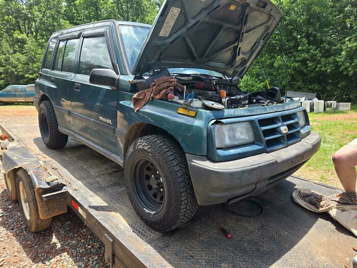 Old SUV with hood open on trailer, showing engine issues mechanics document to prove their work.