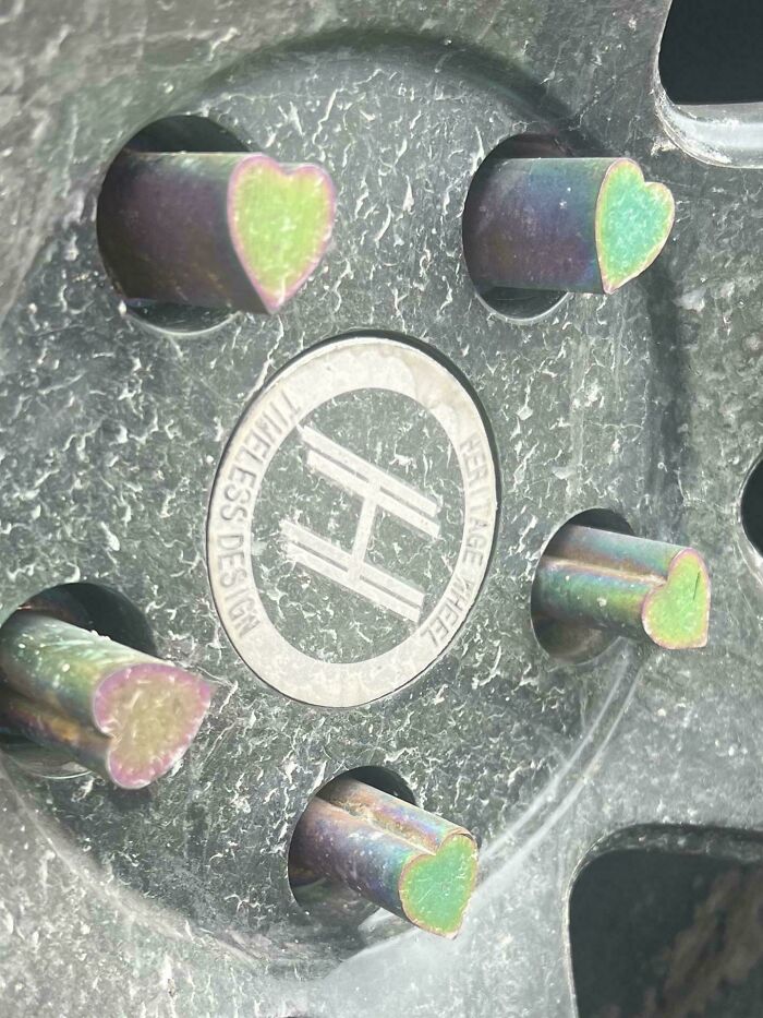 Close-up of a car wheel with unique heart-shaped lug nuts, a rare find for car mechanics to capture in photos.