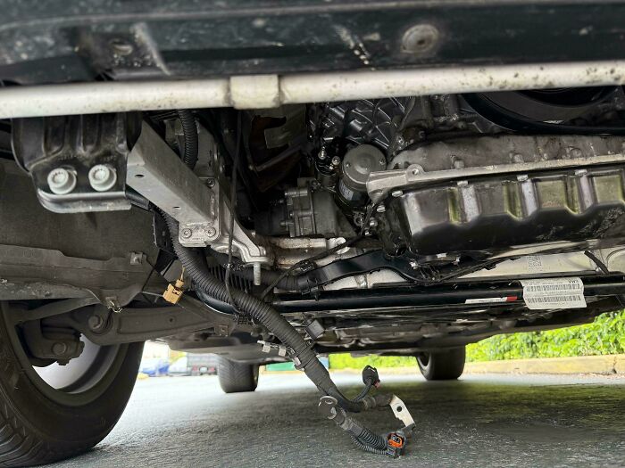 Underside view of a car showing damaged wiring and mechanical parts for car mechanics to document issues.