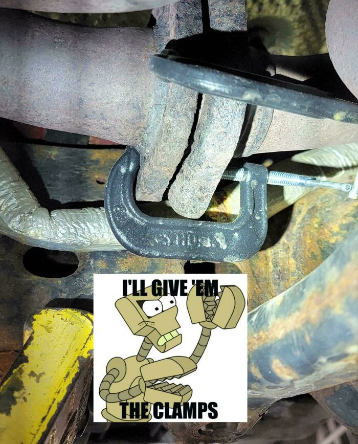 Close-up of a rusty car exhaust pipe temporarily held together with a metal clamp under a vehicle.