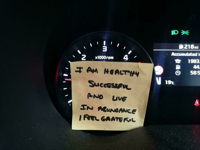 Car mechanic dashboard photo showing a sticky note with a handwritten motivational message inside the vehicle.