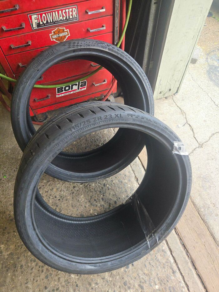 Two car tires with visible inner damage inside a garage with a red tool chest in the background, showing mechanic evidence.
