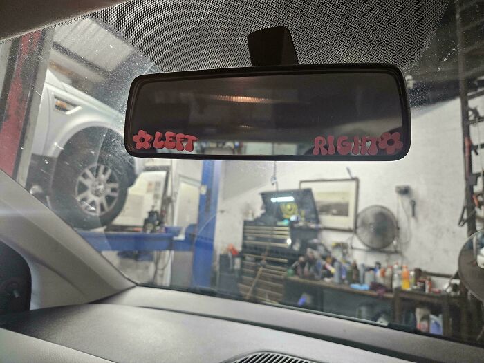Rearview mirror inside a car with Left and Right labels, showing a mechanic shop scene through the windshield.