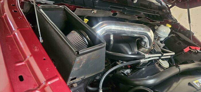 Close-up of a car engine bay showing air intake components and piping that car mechanics had to document.