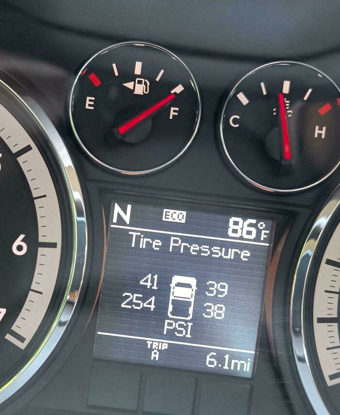 Car dashboard showing tire pressure readings and fuel and temperature gauges from a mechanic's perspective.