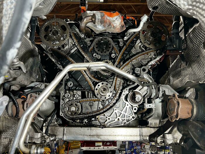 Close-up of a car engine timing chain and mechanics tools showing intricate mechanical parts during repair.