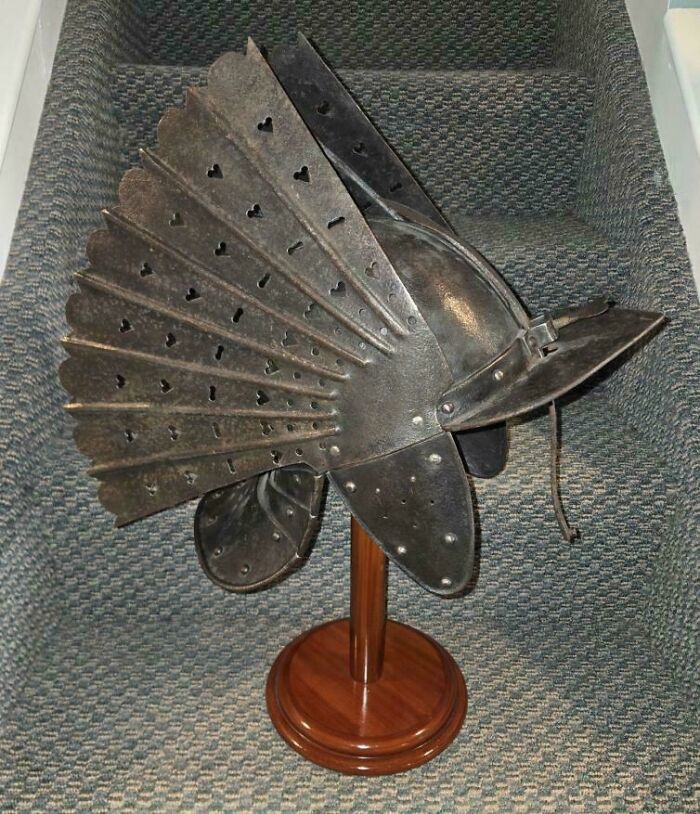 An antique metal helmet with fan-like plates, representing the armor and human history of the Middle Ages.