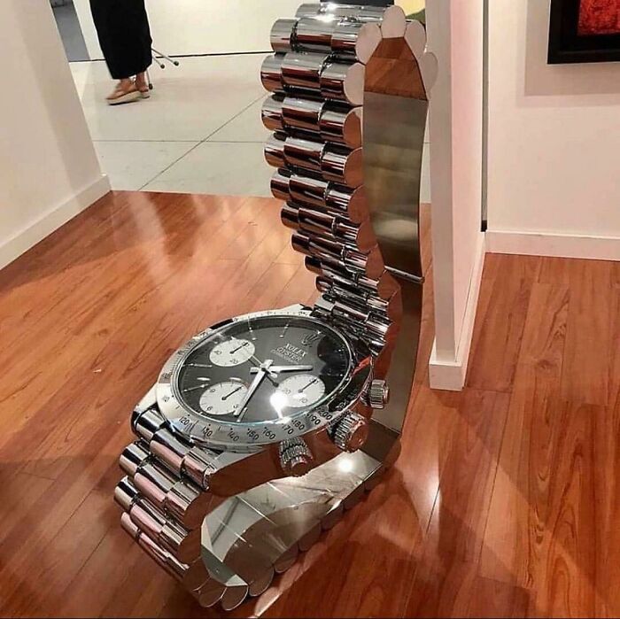 Oversized watch-shaped chair made of reflective metal links, a ridiculous piece of furniture shared online for its unusual design.