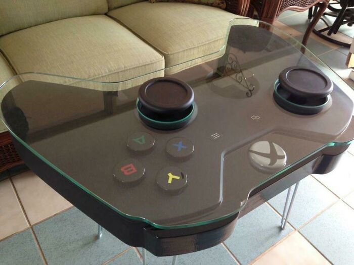 Glass top furniture table designed like a giant video game controller, a ridiculous piece of furniture shared online.