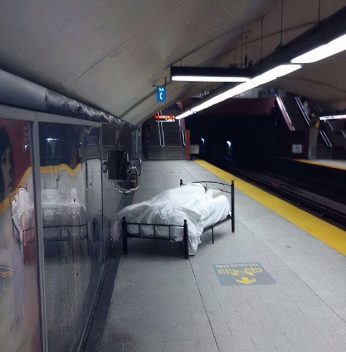 A bed with white sheets placed on a NYC subway platform, showcasing one of the weird moments on the subway.