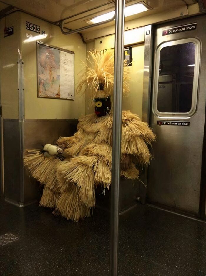 Person in unusual straw costume sitting alone on a NYC subway bench during a weird subway moment.