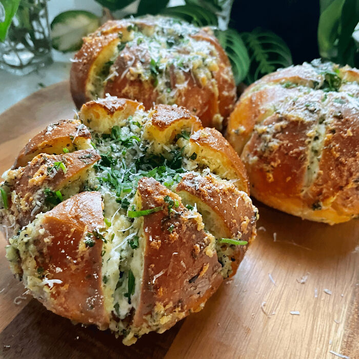 Close-up of homemade garlic bread with herbs and cheese on a wooden board showcasing unique food people have in their country.