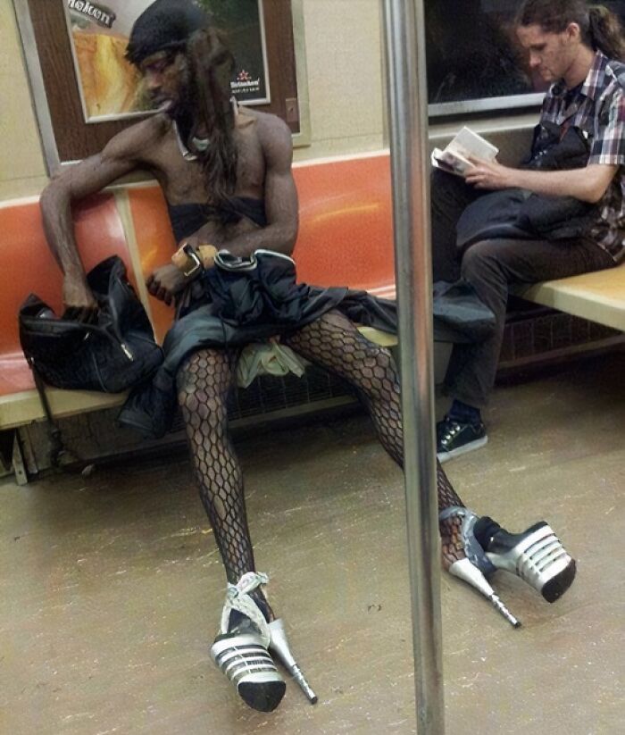 Man in high heels and fishnet stockings sitting on a NYC subway, showcasing one of the weird moments on the subway.