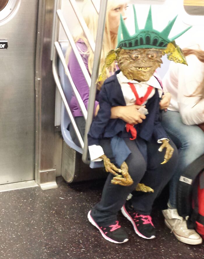 Creature wearing Statue of Liberty hat and suit on NYC subway seat during weird moments on the subway ride