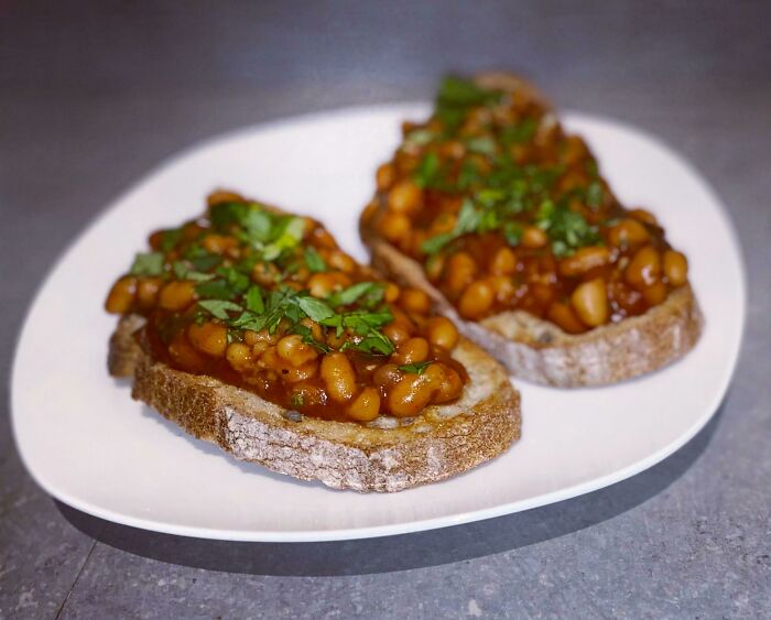 Baked beans on toasted bread garnished with herbs, illustrating things people thought were common everywhere.