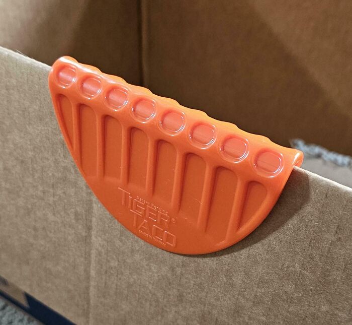Orange plastic tool designed to hold taco shells upright, one of the interesting tools solving annoying little problems.