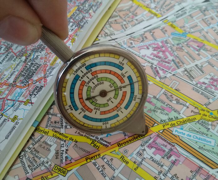 Hand using a measuring tool on a detailed city map, showcasing interesting tools solving small navigation problems.