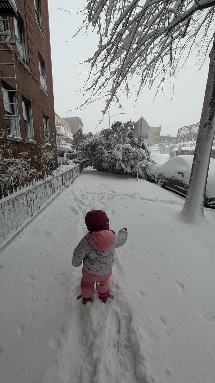 A small child in a snowsuit walks through deep snow, representing the funny, goofy, and great dad moments.