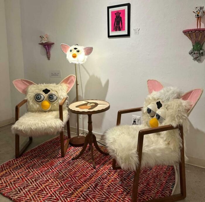 Two ridiculous Furby-inspired chairs and a matching lamp around a small wooden table in a quirky furniture setup.
