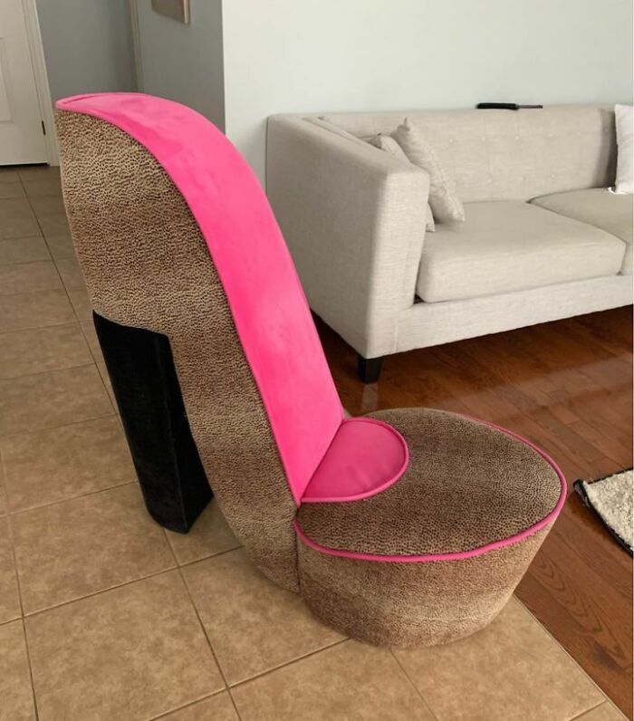 High heel shaped ridiculous piece of furniture with pink and leopard print upholstery in a living room.