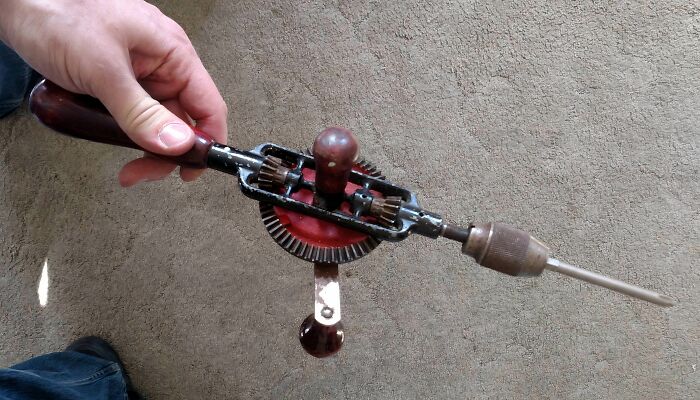 Hand using a vintage hand drill, one of the interesting tools that might solve annoying little problems.