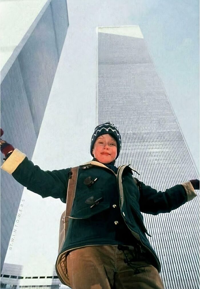 Young child posing with arms outstretched in front of Twin Towers, capturing funny 90s childhood memories.
