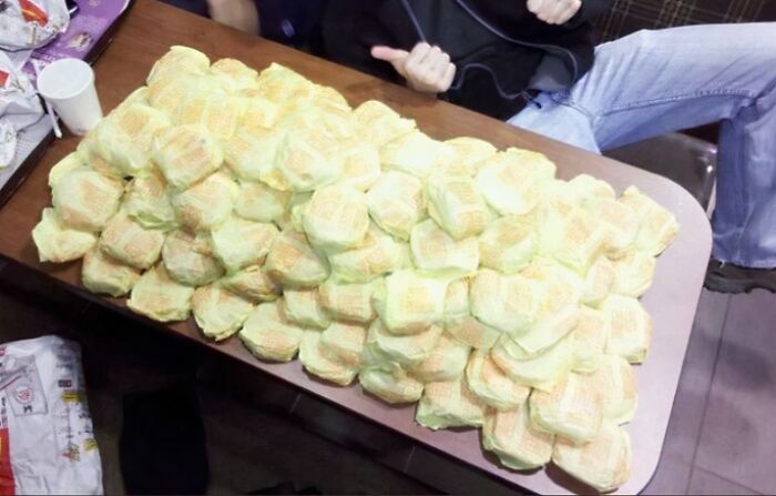 A large pile of '90s fast food burgers stacked on a table, evoking funny ’90s posts and childhood memories.