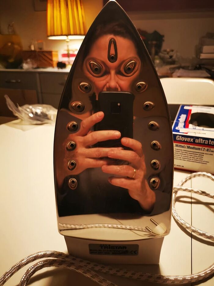 Person’s distorted reflection on a shiny iron with multiple eye-like reflections, illustrating weirdest subreddits popularity.