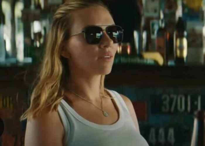 Woman wearing sunglasses and a white tank top in a bar scene illustrating absurd movie and TV details