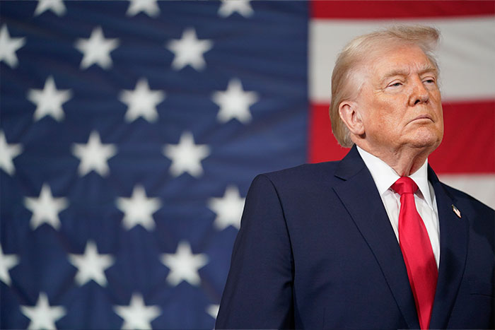 Donald Trump standing in front of an American flag during a formal event amid Stephen King backlash.