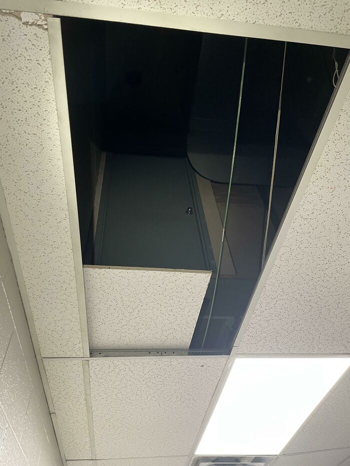 Door leading nowhere visible through ceiling tiles in an office, showcasing architect failure and design flaws.