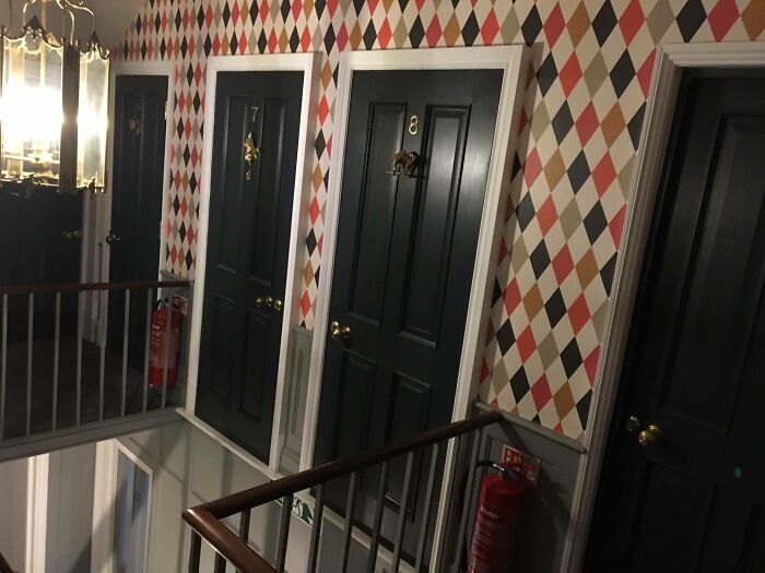 Black doors numbered 7 and 8 lead to nowhere, showcasing an architects fail in door design in a patterned hallway.