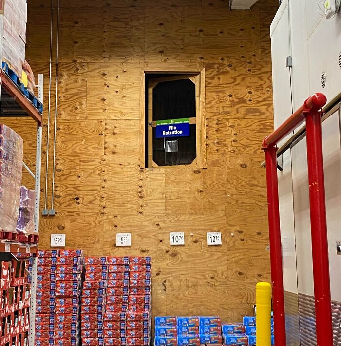 A door high on a wooden wall inside a warehouse leads to nowhere, illustrating architect design failure.