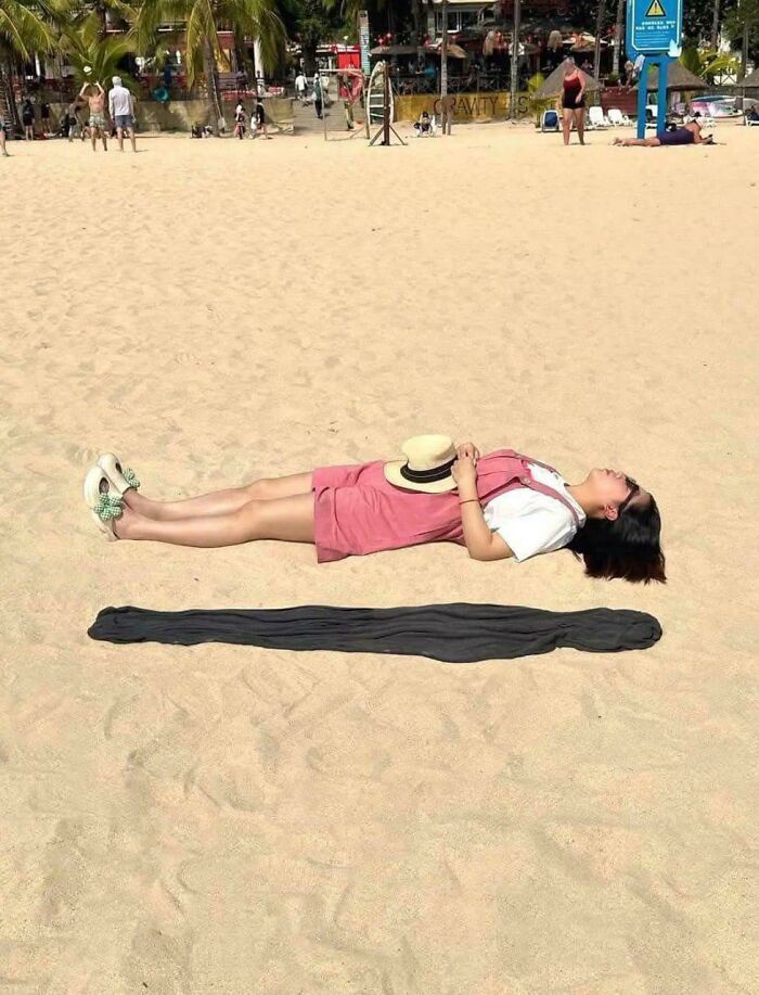 Amazing photos of a person lying on a sandy beach with a hat, new pics featuring a dark shadow.