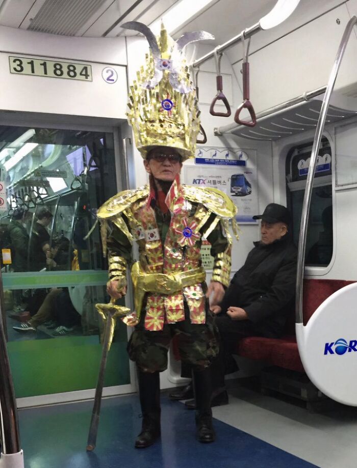 Man wearing an elaborate golden costume and crown inside a subway car, showcasing weird moments on the NYC subway.