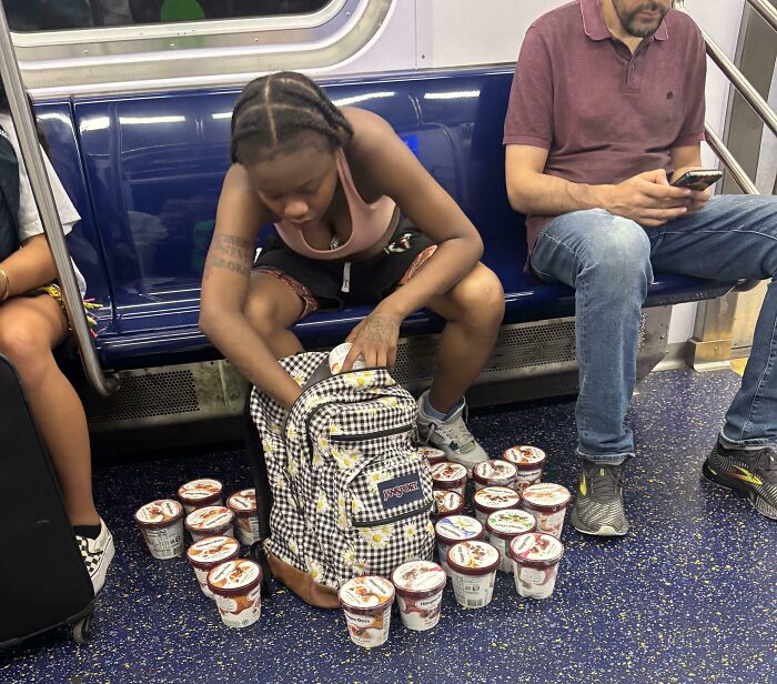 Woman on NYC subway placing multiple ice cream containers from floor into backpack among weird moments on the subway.